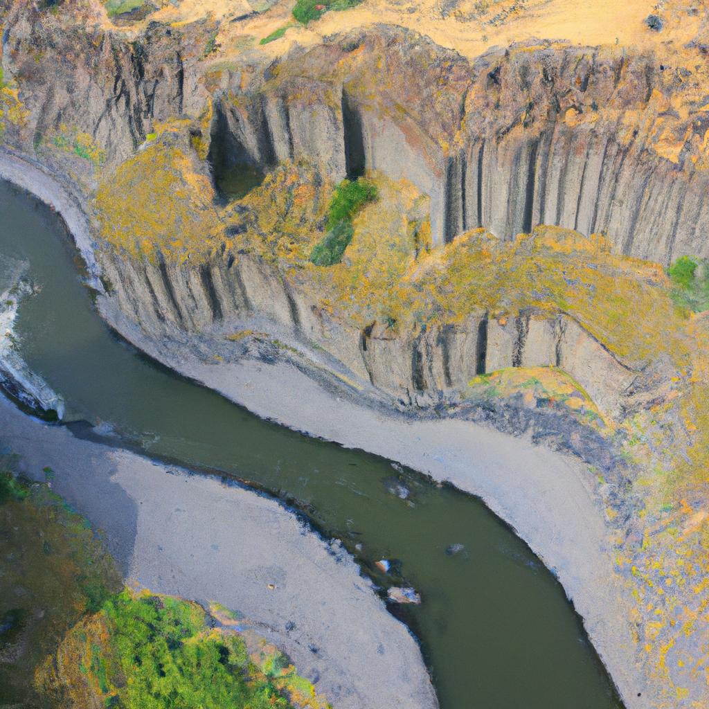 The river meanders through the valley, carving a path through the imposing basalt column formations that tower over it