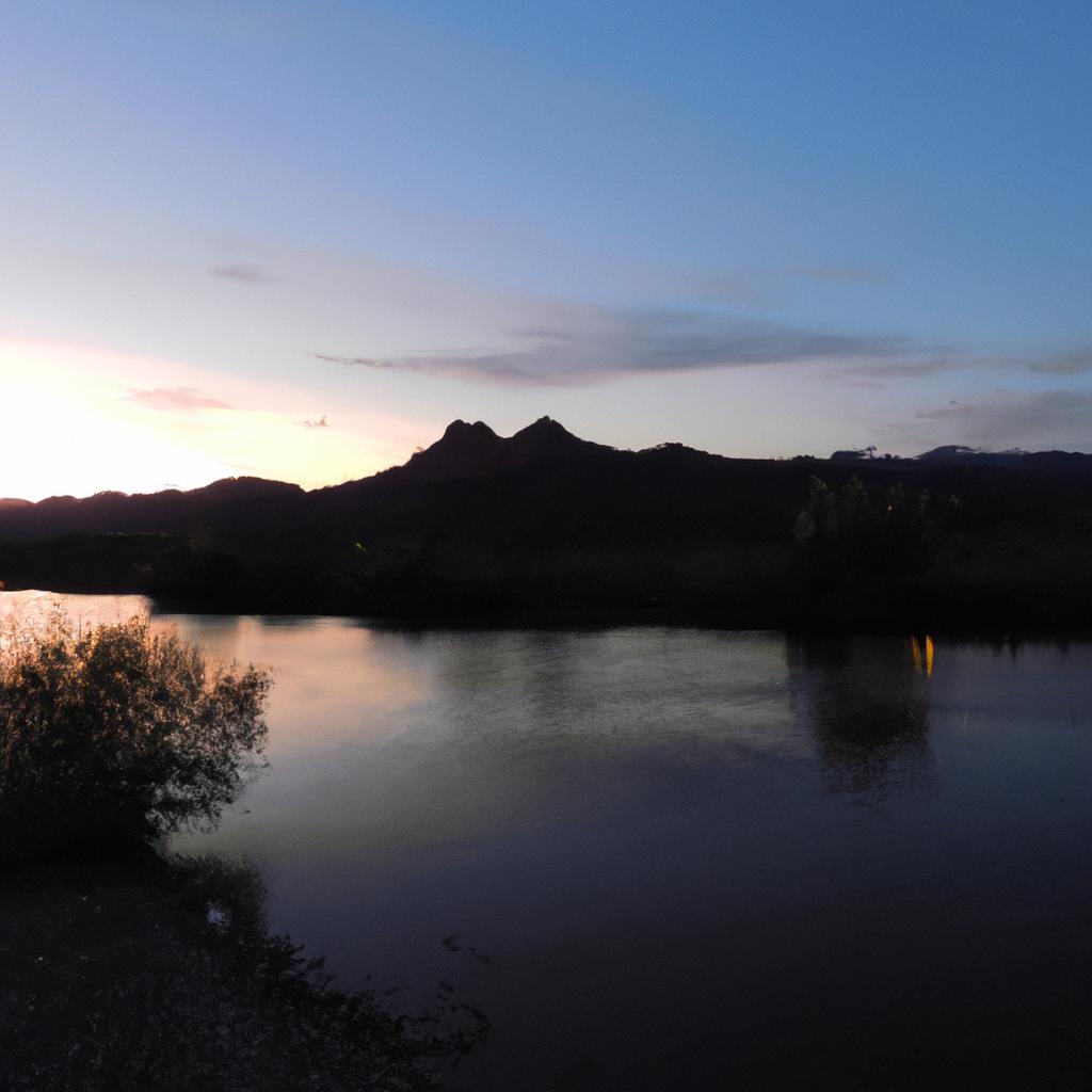 The beautiful colors of the sunset reflect off the river, creating a picturesque view.